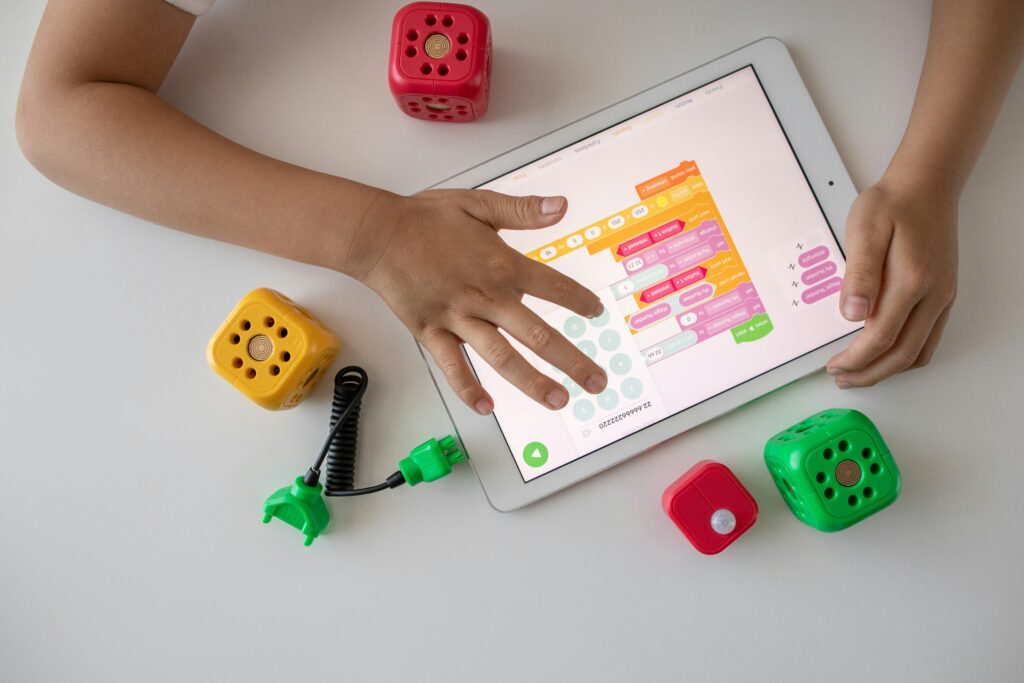 children's hands using a digital tablet for visual programming