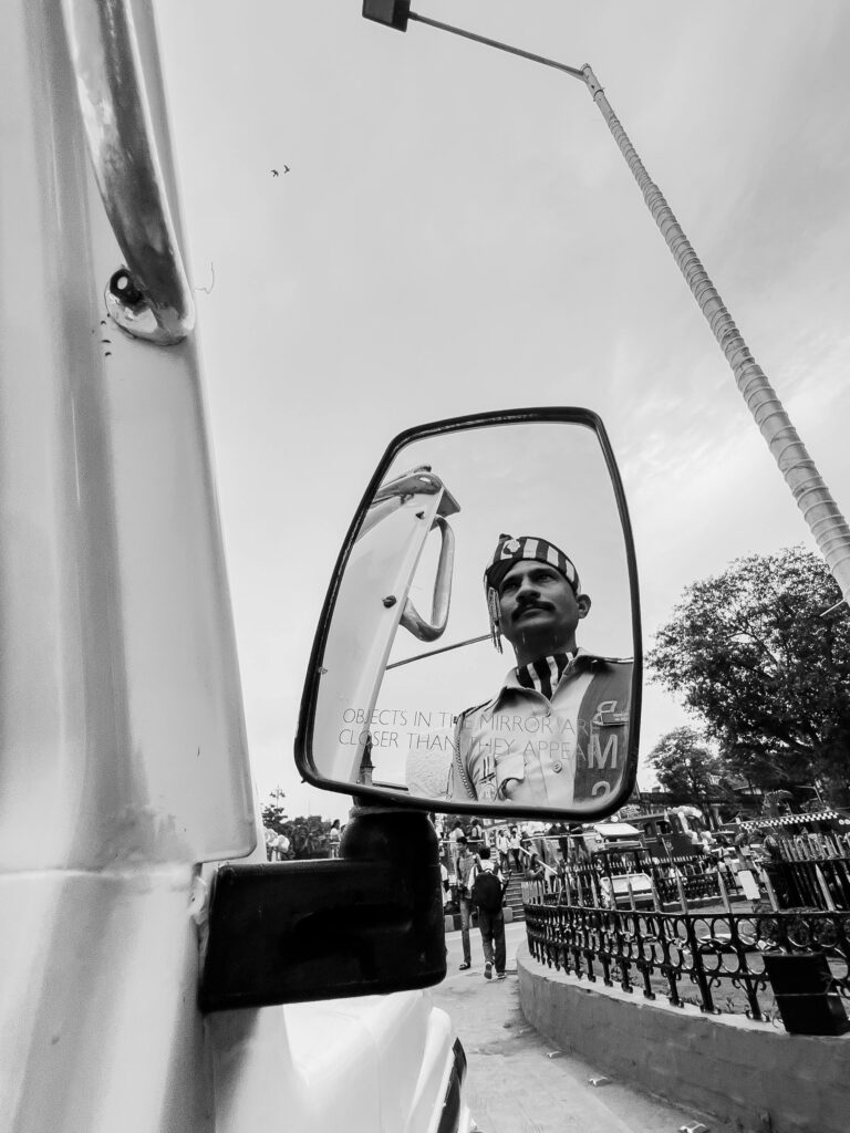 Reflection of a soldier in a side mirror on a city street in black and white.